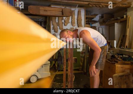 Assistent Pietro Meneghini inspiziert ein Holzruder in der Werkstatt des venezianischen forcola und des Ruderherstellers Saverio Pastor, Handwerker, Kunstgegenstand, Venedig, Ital Stockfoto