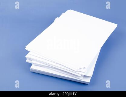 Stapel leerer A4-Blätter auf blauem Hintergrund. Stockfoto