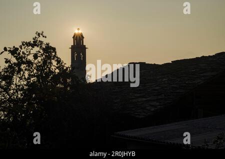 Die Sonne scheint hinter einem Kirchturm im Dorf Soglio, Val Bregaglia, Kanton Grison, Schweiz Stockfoto