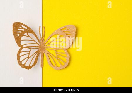 Schmetterling aus geschnitztem Papier oder Schneidepapier auf gelbem Hintergrund mit leerem Platz für Ihren Text oder Ihre Nachricht. Stockfoto