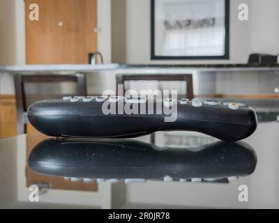 Schwarze Fernbedienung, die auf einem Spiegeltisch in einem Hotelzimmer reflektiert wird Stockfoto