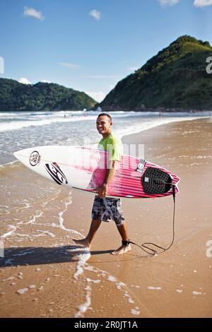 Surfer Rafael, 100% Jesus Schriftzug auf seinem Brett, Praia do Tombo, im Westen der Stadt, Guaruja, Costa Verde, Sao Paulo, Brasilien Stockfoto