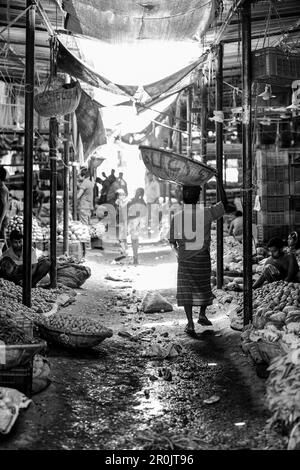 Ein Mann mit einem Korb auf dem Kopf auf einem lokalen Markt, Dhaka, Bangladesch Stockfoto