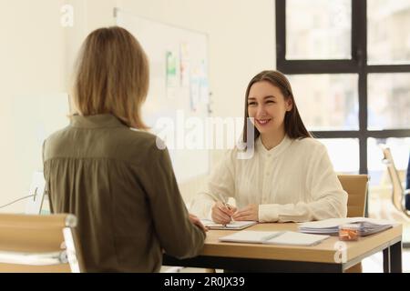 Geschäftsfrau, die mit dem Kunden kommuniziert und sich im Büro Notizen macht Stockfoto