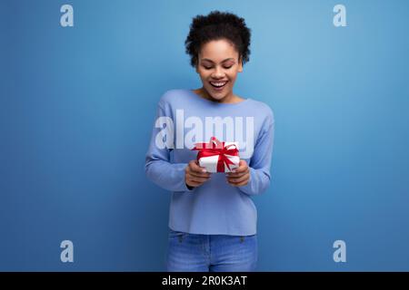 Junge brünette Frau mit Afrohaar bekam ein Geburtstagsgeschenk Stockfoto