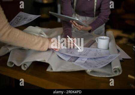 Professionelle Modedesigner prüfen das Design neuer Modellskizzen, erstellen Brainstorming und arbeiten gemeinsam im Kreativbüro. Zugeschnittenes Bild Stockfoto