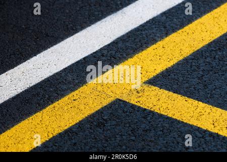 Straßenmarkierung auf brandneuer Asphaltoberfläche eines Parkplatzes, gelbe und weiße Linien als abstrakter Hintergrund in Perspektive Stockfoto