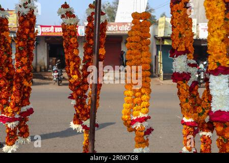 Blumengirlanden aus Marigold-Blumen und Rosenblumen hängen in einem Straßenladen in Indien. Galrnads oder Mala Road Shops verkaufen für Temple o Stockfoto