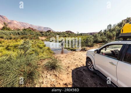 Vor der Überquerung des Ugab von Kunenen nach Erongo überprüft der Fahrer die Wassertiefe. Im Hintergrund der Brandberg, Erongo, Damaraland Stockfoto
