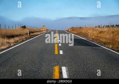 Straße, die den Hügel hinauf in Richtung Nebelgebirge führt, nahe Middlemarch, Maniototo, Otago, Südinsel, Neuseeland Stockfoto