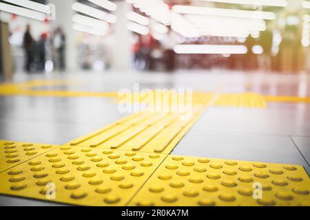 Gelber taktiler Gehweg für die Jalousien auf dem Boden im Einkaufszentrum Stockfoto