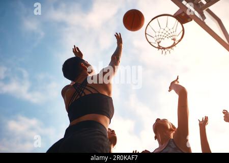 Auf den Sieg. Eine vielfältige Gruppe von Sportlerinnen, die tagsüber gemeinsam ein Wettkampfspiel mit Basketball spielen. Stockfoto