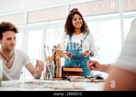 Kein Freund ist ein Unfall. Eine attraktive junge Künstlerin steht und spricht mit ihren Freunden während einer Kunstsitzung im Studio. Stockfoto