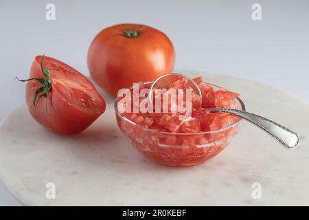 Eine kleine Schüssel gefüllt mit gewürfelten Tomaten, die auf einem Holztisch ruht. Stockfoto