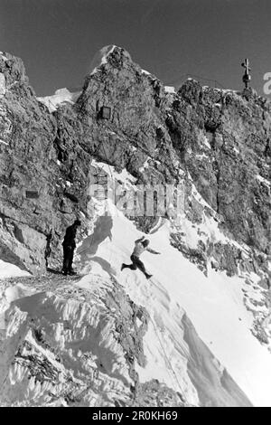 Ein Mann springt in einer Schneewehe auf dem Gipfel der Zugspitze, 1936. Ein Mann springt auf dem Gipfel der Zugspitze, 1936, in eine Schneeverwehung. Stockfoto