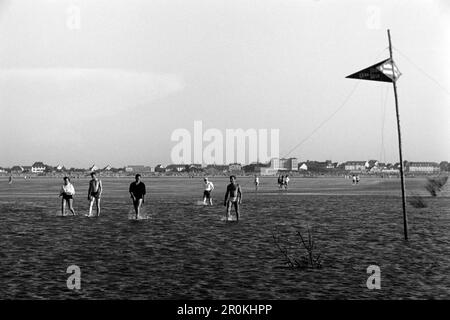 Badegästen spazieren im Watt bei Duhnen, Stadtteil von Cuxhaven, 1960. Badende, die in den Schlammgebieten bei Duhnen, Bezirk Cuxhaven, 1960, spazieren. Stockfoto