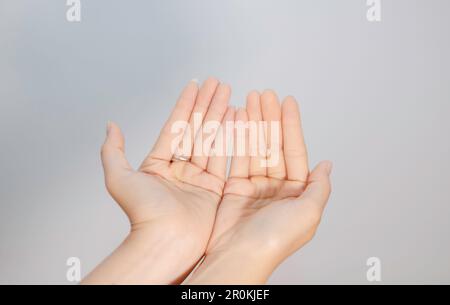 Zwei leere, schöne weibliche Hände mit Handflächen nach oben, Nahaufnahme von oben, isoliert auf weißem Hintergrund Stockfoto