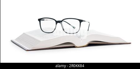 Die Lesebrille auf dem geöffneten Buch isoliert auf weißem Hintergrund. Stockfoto