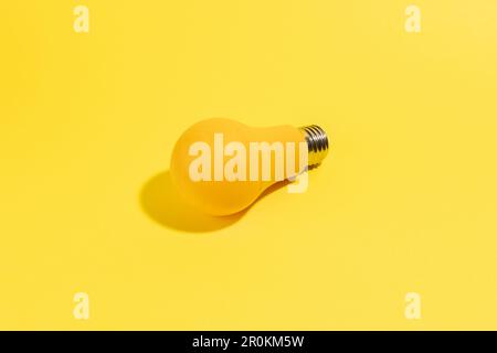 Gelbe Glühlampe auf gelbem Hintergrund, minimalistischer Stil Stockfoto