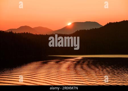 Die goldene Sonne erhebt sich hinter den Bergen, die vom Expeditionsschiff MS Bremen (Hapag-Lloyd Cruises), Milbanke Sound, Inside Passage, zwischen Denny, aus gesehen werden Stockfoto