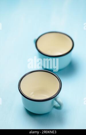 Blaue leere emaillierte Becher auf einem Holztisch. Stockfoto