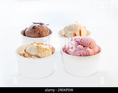 Vanille-Karamell-Eiscreme aus weißer Schokolade in einem Pappbecher ohne Markenkennzeichnung mit Plastiklöffel. Stockfoto