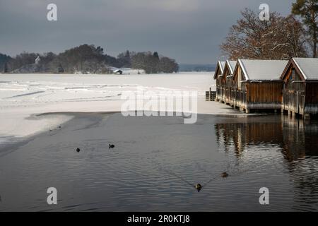 Winter am teilweise gefrorenen Staffelsee mit Blick auf die Bootshäuser und die Insel Wörth mit Simpertkapelle (St. Bonifatius), Seehausen, Oberbayern, Stockfoto