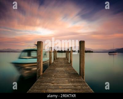 Blick über eine Fußgängerbrücke zur Fraueninsel und den Chiemgau-Alpen an einem Sommerabend, Gstadt am Chiemsee, Oberbayern, Deutschland Stockfoto