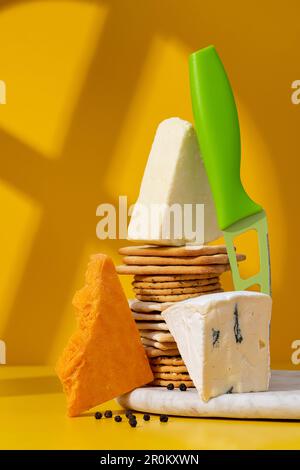 Set oder Sortiment mit Käse und Crackern. Rotes Stilton, Cambozola, Brie, Cheddar, hausgemachte rote Johannisbeermarmelade und Cracker auf weißem Marmorbrett und Schrei Stockfoto