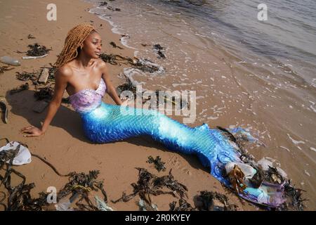 REDAKTIONELLE VERWENDUNG NUR Chisanga Mwila, gekleidet als Ariel von der kleinen Meerjungfrau am Cullercoats Beach, Newcastle, vor dem Live-Remake des Films 2023 als Teil einer Sensibilisierungskampagne des nachhaltigen Toilettenpapierunternehmens Oceans, die die negativen Auswirkungen der Meeresverschmutzung an der britischen Küste hervorhebt. Ausgabedatum: Dienstag, 9. Mai 2023. Stockfoto