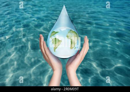 Eine Frau, die die Ikone der Erde auf blauem Hintergrund hält, Nahaufnahme. Wassersparkonzept Stockfoto
