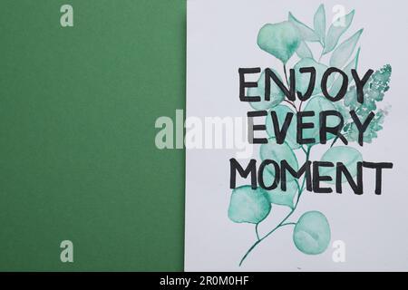 Karte mit Satz Genießen Sie jeden Moment auf grünem Hintergrund, Draufsicht. Platz für Text Stockfoto