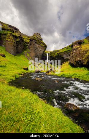 Felsige Landschaft um den Kvernufoss Wasserfall mit Fluss im Vordergrund: Island, Europa Stockfoto