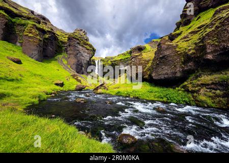 Felsige Landschaft um den Kvernufoss Wasserfall mit Fluss im Vordergrund: Island, Europa Stockfoto