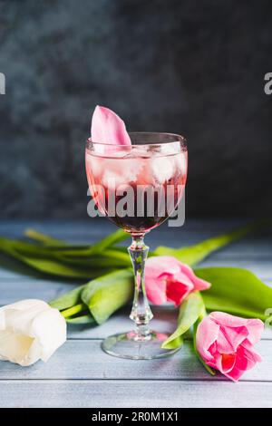 Rosa Cocktail mit Champagner oder Prosecco und Eis in Kristallweinglas und weißen Tulpen Stockfoto