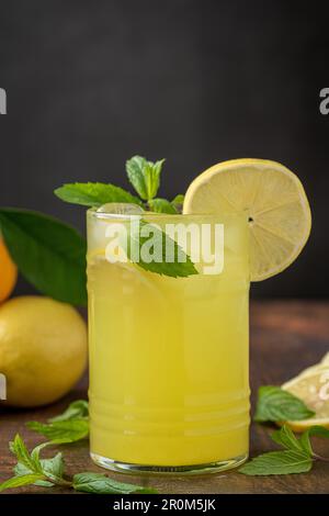 Limonade mit frischen Minzeblättern und Zitronenscheibe in Glas auf einem Holztisch Stockfoto