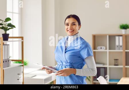 Porträt einer jungen Ärztin in blauer medizinischer Uniform, die in die Kamera schaut. Stockfoto