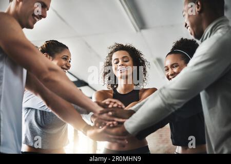 Umgeben Sie sich mit Menschen, die Sie dazu motivieren, sich selbst zu verbessern. Eine Gruppe junger Menschen, die sich in einem Fitnessstudio solidarisch zusammentun. Stockfoto