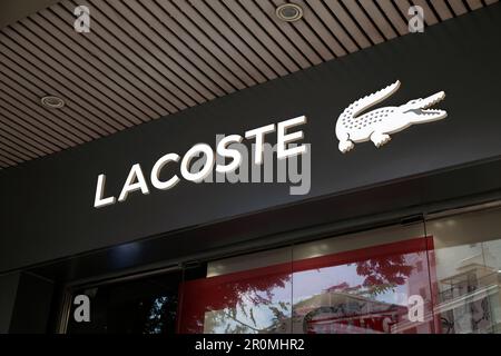 Ho-Chi-Minh-Stadt, Vietnam - 1. Mai 2023: Handelsschild für Modegeschäfte mit schwarzweißem Lacoste-Logo. Berühmtes Logo einer Luxusmarke über einem Stockfoto