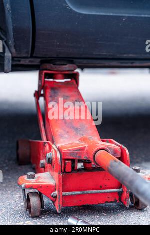 Austausch von Fahrzeugrädern. Das Fahrzeug mit einem hydraulischen Wagenheber anheben. Stockfoto
