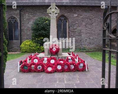 War Memorial auf dem Gelände der St. Marys Church aus dem Mittelalter im Stadtzentrum von Bulward, Brecon Powys Mid Wales UK, bedeckt mit rotem Mohn Stockfoto