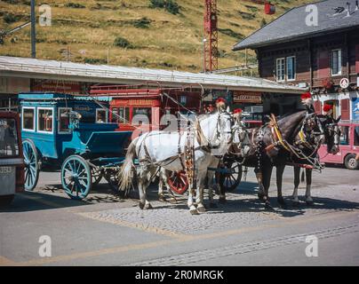 Straßenszene im Schweizer Alpenort Zermatt mit Pferdekutschen vor dem Bahnhof Zermatt Stockfoto