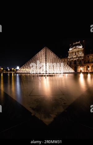 Beleuchtete Pyramide im Louvre bei Nacht, Lichtreflexionen im Brunnenbecken vor der Glaspyramide, Île-de-France, Paris, Frankreich Stockfoto