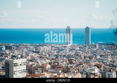 Aus der Vogelperspektive sehen Sie die malerische Stadt mit Wolkenkratzern und Wohngebäuden auf den Straßen Barcelonas vor dem endlosen blauen Meer Stockfoto