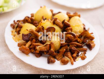 Leckere gebratene Pfifferlingpilze mit neuen Kartoffeln auf weißem Teller Stockfoto