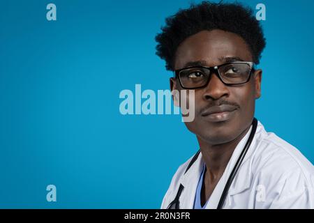 Attraktiver afroamerikanischer Arzt mit Brille, blauer Hintergrund Stockfoto