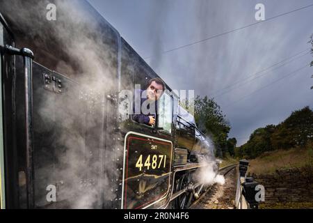 Der Zugführer wartet auf die grüne Flagge, die vom Bahnhof Haworth abfährt. Stockfoto