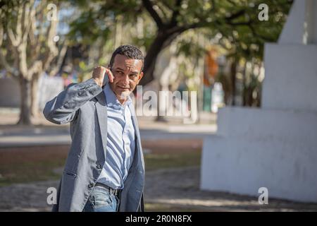 Junger Latino-Mann, der mit dem Handy spricht, von hinten gesehen. Stockfoto