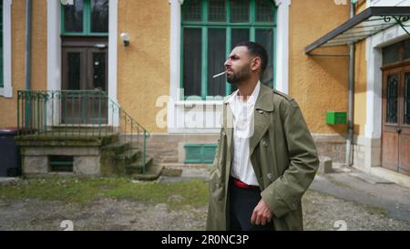 Ein seriöser Araber zündete eine Zigarette an, während er mit nachdenklichen Emotionen draußen stand Stockfoto