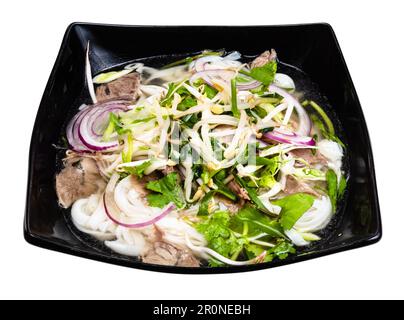 Vietnamesische Suppe Pho Bo mit Reisnudeln, Brühe, Zwiebeln, Gemüse, Rindfleisch in der Schüssel, Ausschnitt auf weißem Hintergrund Stockfoto